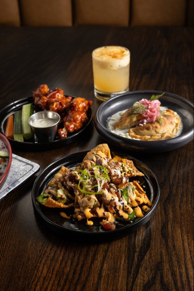 Tuna nachos on wonton chips with jalapeno, sriracha mayo and eel sauce, beside
                    wings and gyro empanadas.