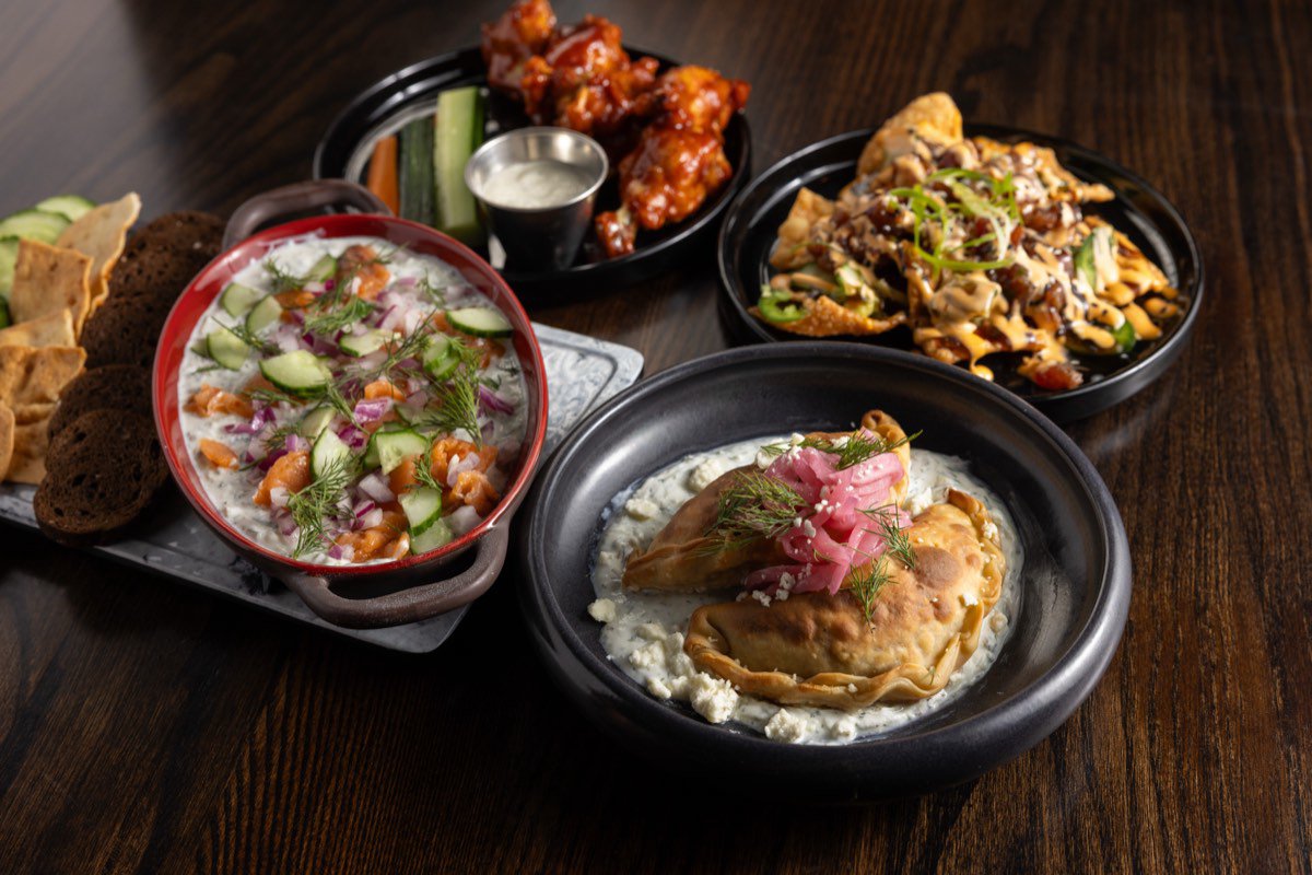 Salmon dip with rye crisps and cucumber beside gyro empanadas on mint tzatziki,
                    chicken wings and tuna nachos.