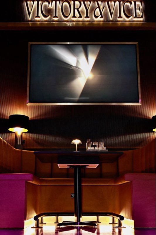 A private booth with its own screen beneath the Victory & Vice sign.