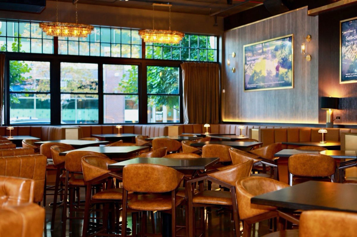 The dining room in daylight, leather chairs under the chandeliers.
