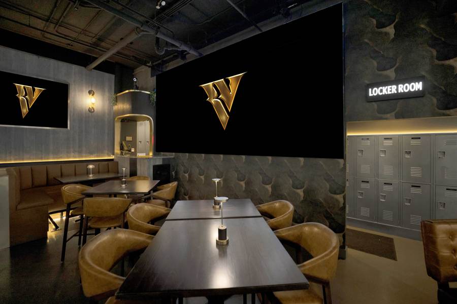 The Locker Room: leather chairs, lockers along the wall and the lit V on the screen.