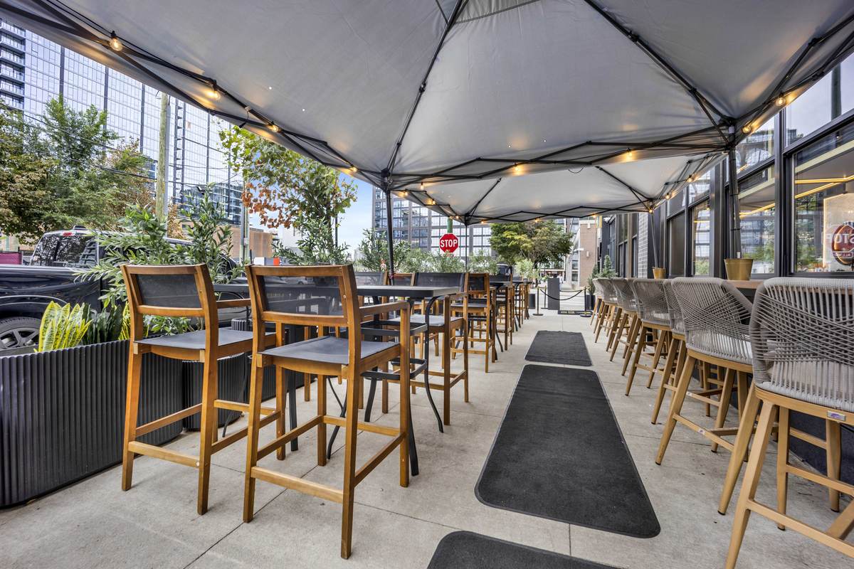 The patio under its canopy, high-top seats lined along the sidewalk.