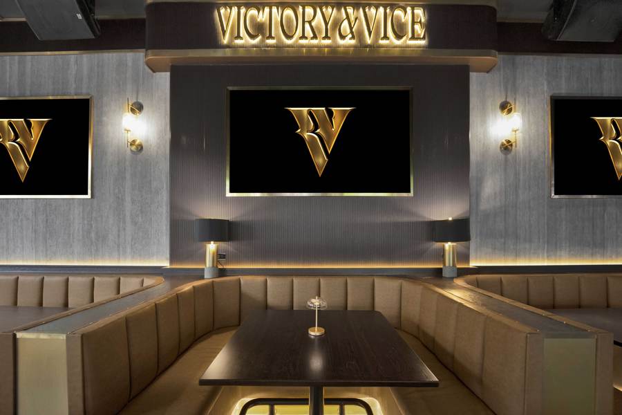 A curved leather booth under the gold Victory & Vice sign.