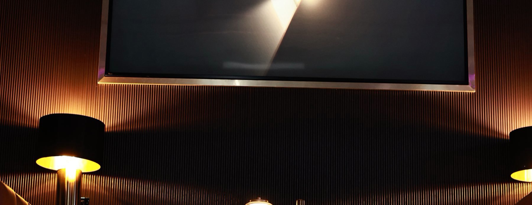 A packed room under the smoke, the screen lit behind the crowd.