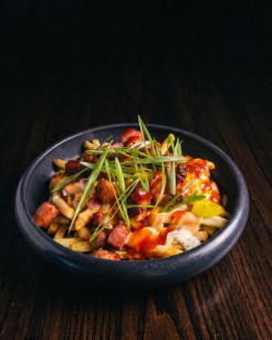 A bowl of loaded fries with banana peppers and green onion.