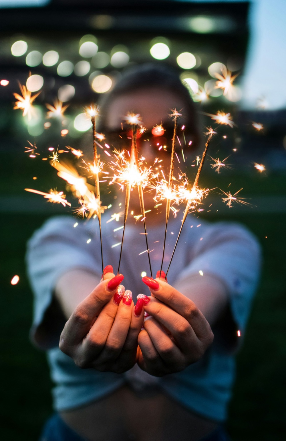 Hands holding a bunch of lit sparklers.